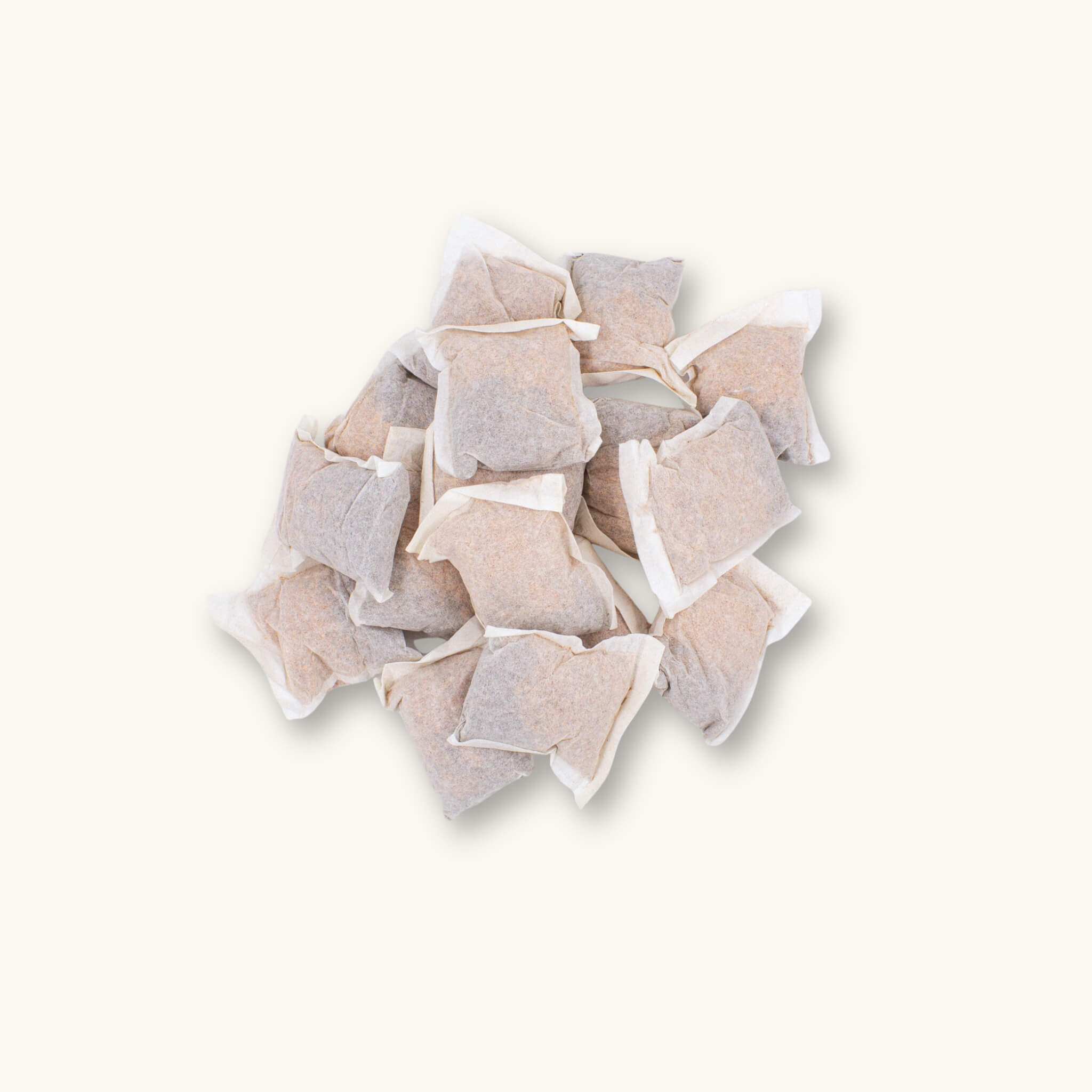 A pile of 16 Betta Tea bags containing maroon botanicals, photographed on a natural background at Betta Botanicals.