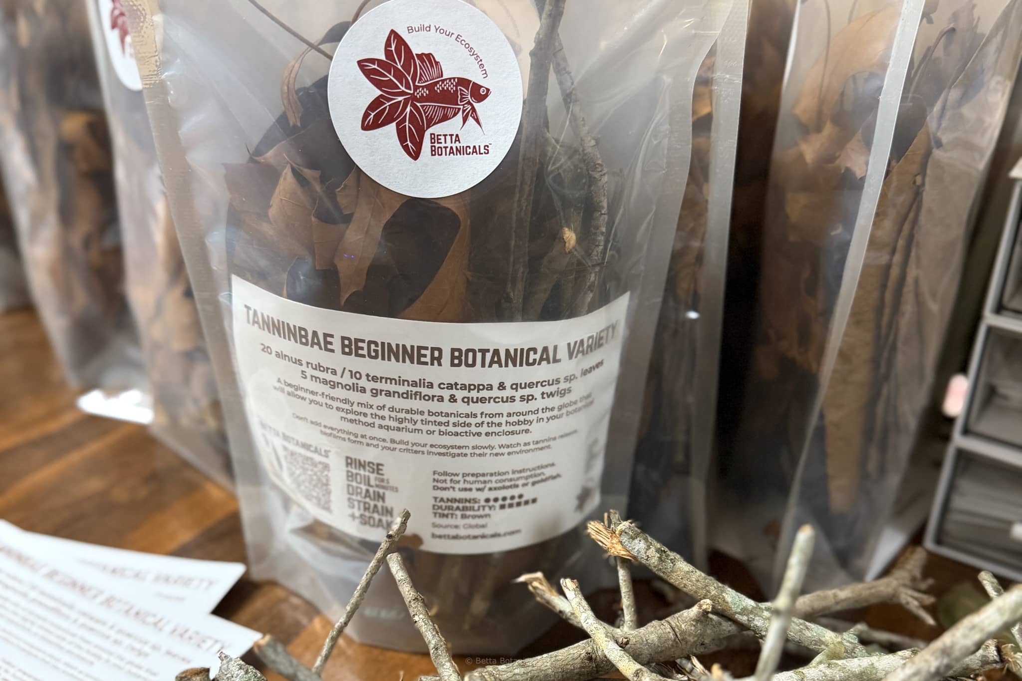 A transparent and compostable bag of beginner friendly botanicals being packaged on a dark brown desk at Betta Botanicals.