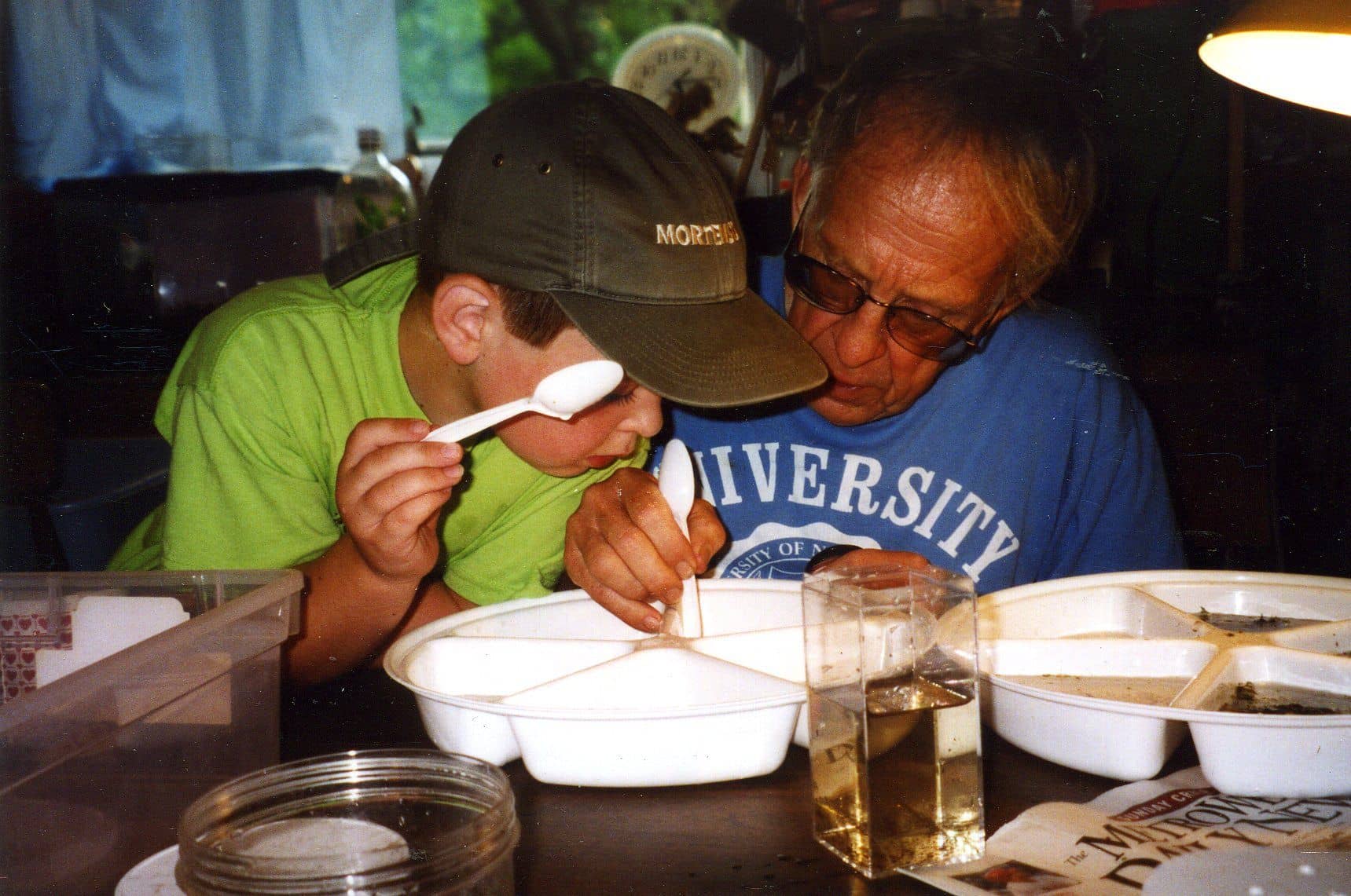 A grandfather and grandson looking at aquatic micro- and macro-fauna in a garage together at Betta Botanicals.