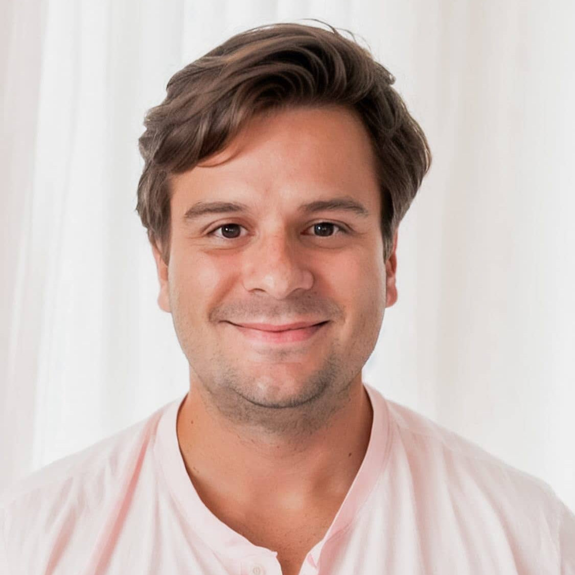 A person smiling at the camera with brown hair against a white background.