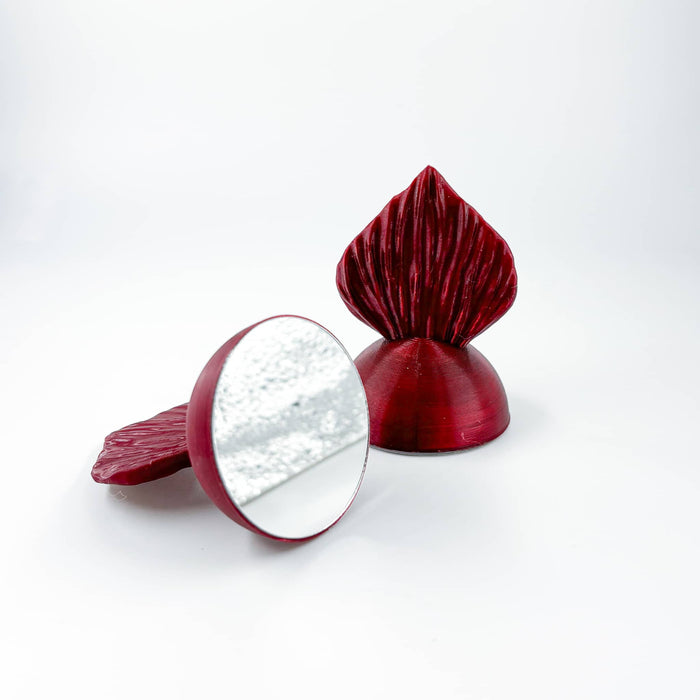Two red hand held betta flare mirrors with a fish tail for a handle at Betta Botanicals.