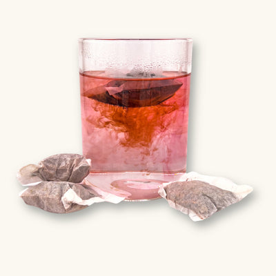A clear glass jar of red tinted aquarium tannins from tea bags of Betta Tea by Betta Botanicals.