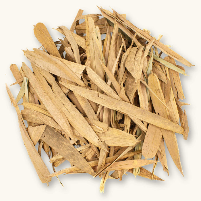 A pile of slender tan Colombian Bamboo leaves (Bambusa sp.) for dart frog vivariums, photographed on a natural background at Betta Botanicals.