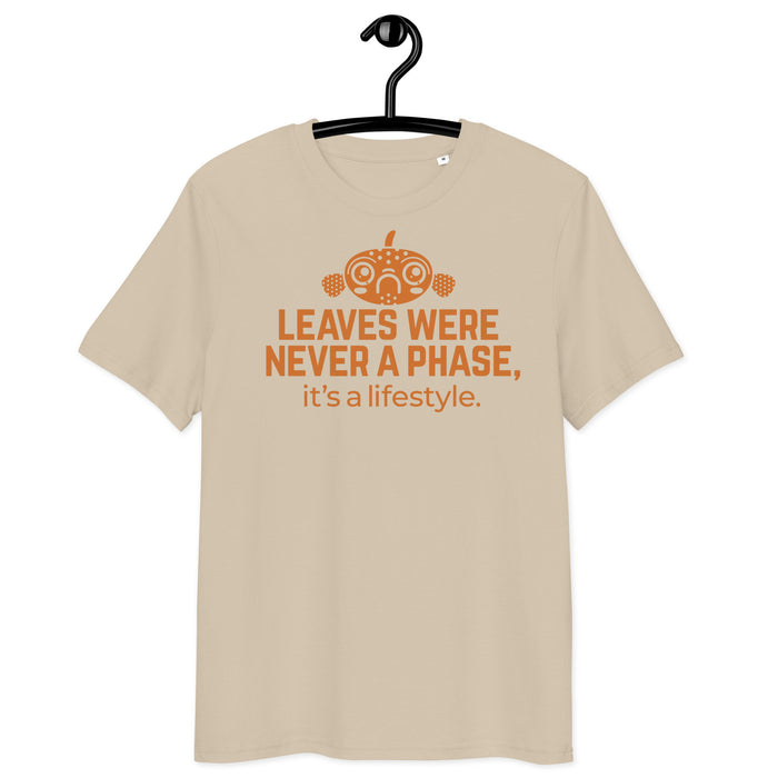 A beige organic cotton t-shirt featuring the phrase ‘Leaves were never a phase, it’s a lifestyle.’ in bold orange print, with a decorative fish design above the text, displayed on a hanger.