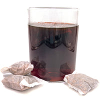 A clear glass jar of brown/amber aquarium tannins from Betta Tea with three tea bags of Betta Tea by Betta Botanicals.