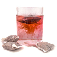A clear glass jar of red/brown tinted aquarium tannins from tea bags of Betta Tea by Betta Botanicals.